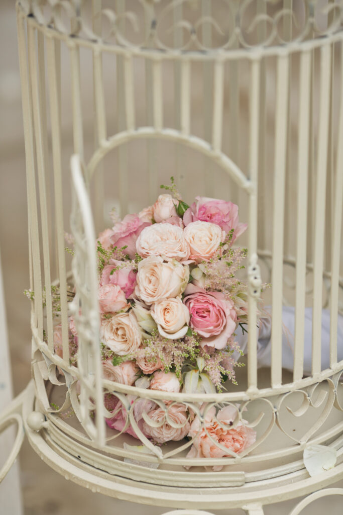 Bride's pink boquet stands in bird cage